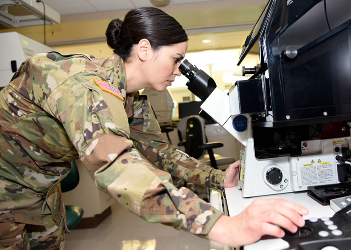Capt. Elaine Por looking through a microscope