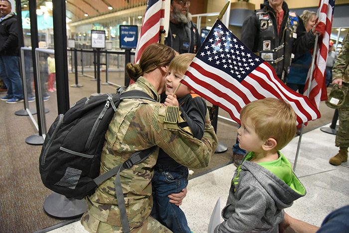 U.S. Army Spc. Kallie Kappes kneels to hug her sons