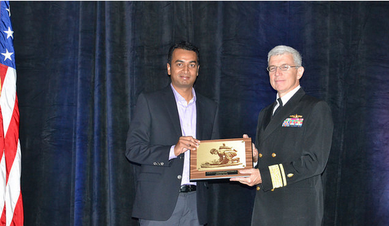 Dr. Vineet Rakesh accepts the Silver Award of Excellence from Rear Adm. Bruce A. Doll