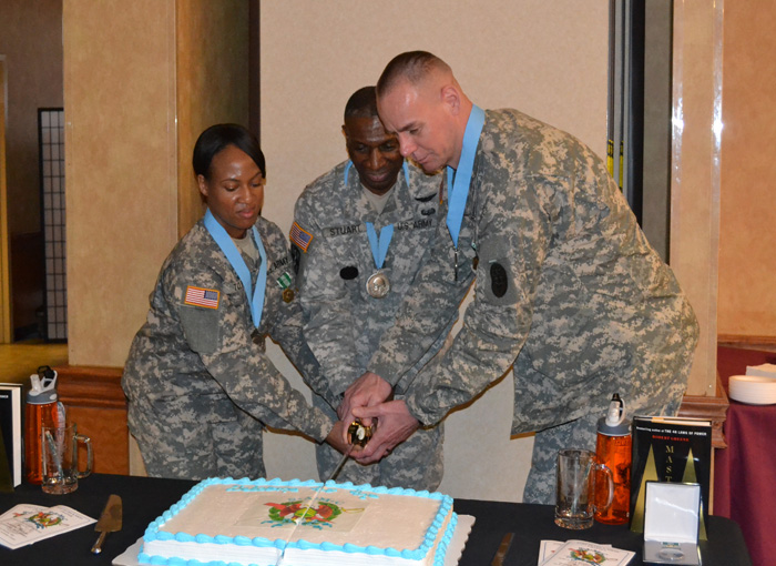 Staff Sgt. LaDonna Tolbert (left) and Staff. Sgt. Patrick Omara (right) cut the celebratory cake with Command Sgt. Major Kevin B. Stuart, USAMRMC command sergeant major