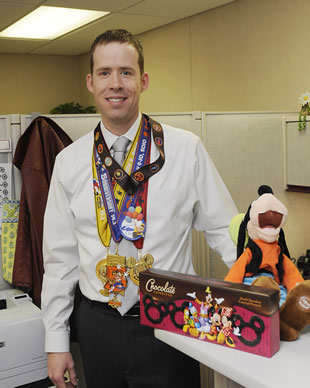 Matt Gray, budget analyst for the Blast Injury Research Program Coordinating Office, poses with his Disney medals, Disney chocolates, and a Goofy souvenir his boss bought to congratulate him. Gray ran three races, two of which were marathons.