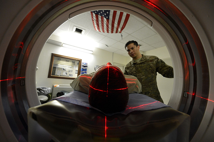 A service member positions a patient for a CT scan